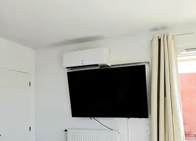 a flat screen tv hanging on a wall next to a window at Lakeside Provence - Appartement classé 4 étoiles, Vue sur le lac de Monteux, Parking sous-sol, double clim in Monteux
