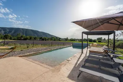a swimming pool with lounge chairs and an umbrella at Domaine Mas Côté Cour in Maubec