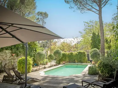 a pool with chairs and an umbrella next to a yard at Villa Martinet in Carpentras