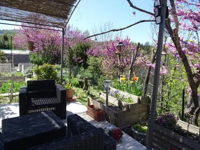 a patio with chairs and flowers in a garden at Chambre indépendante in Apt