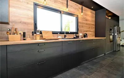 a kitchen with black cabinets and a large window at 3 Bedroom Amazing Home In Montfavet in Montfavet