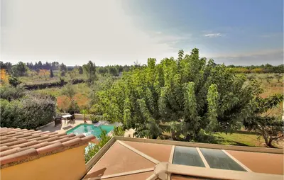 a swimming pool with chairs and a tree next to a house at Stunning Home In Châteaurenard in Châteaurenard