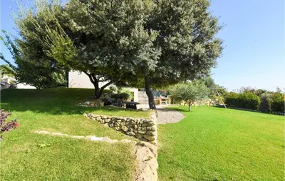 a tree and a stone wall in a yard at Gorgeous Home In Puget in Puget