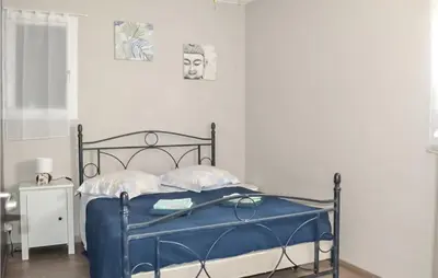 a bedroom with a blue bed with two pictures on the wall at Gorgeous Home In Puget in Puget