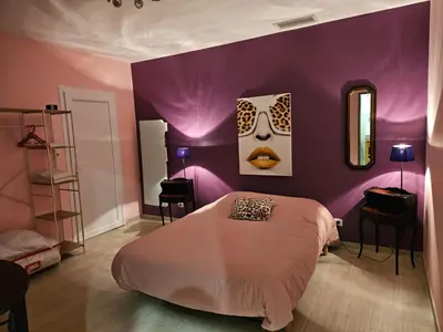 a bedroom with a bed and a purple wall at AUPETIT BONHEUR in Lauris