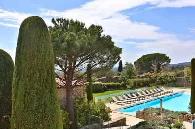 a pool in a garden with lounge chairs and trees at Le Bastidon de Guillemette in Gordes