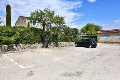 a car parked in a parking lot next to a building at Le Bastidon de Guillemette in Gordes