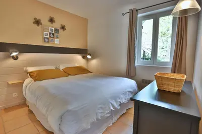 a bedroom with a bed and a desk and a window at Le Bastidon de Guillemette in Gordes