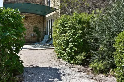 a chair sitting outside of a building with bushes at Le Bastidon de Guillemette in Gordes