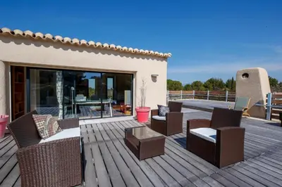 a wooden deck with chairs and a table on it at Sérénité en Provence, Climatisée in La Roque-sur-Pernes