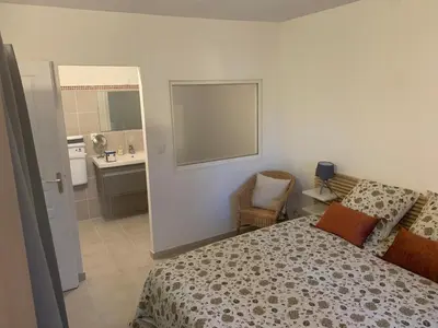 a bedroom with a bed and a bathroom with a sink at la pinède in Roussillon