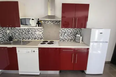 a kitchen with red cabinets and a white refrigerator at maison village vacances demeures du Ventoux in Aubignan