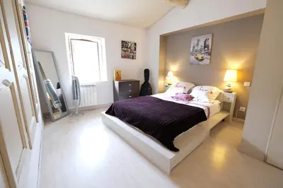 a bedroom with a bed with purple sheets and a window at charming provencal house with private pool for 4 people in cheval blanc, luberon. in Cheval-Blanc