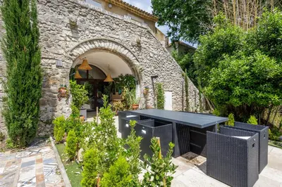 a stone wall with a black table in a garden at Errances Provençales in Saint-Rémy-de-Provence
