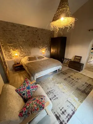a bedroom with a bed and a couch and a chandelier at Le Mazet de l'Isle sur la Sorgue in Saumane-de-Vaucluse