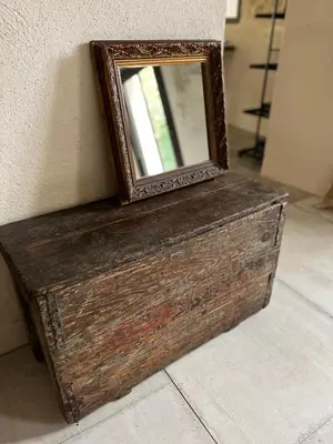 a mirror sitting on top of a wooden box at Le Mazet de l'Isle sur la Sorgue in Saumane-de-Vaucluse