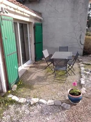 a table and chairs outside of a house with green doors at Single storey 40m² bordering pine forest and spa in Noves