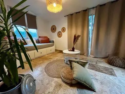 a living room with a bed and a potted plant at Aix-en-Provence, Maison provençale au calme de la campagne avec Jacuzzi in Aix-en-Provence