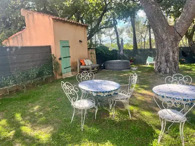 two tables and chairs in a yard with a tree at Aix-en-Provence, Maison provençale au calme de la campagne avec Jacuzzi in Aix-en-Provence