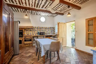 a kitchen with a table and chairs in a room at La maison du château in Fontaine-de-Vaucluse