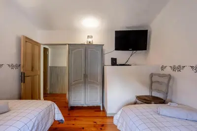 a bedroom with two beds and a tv on the wall at La maison du château in Fontaine-de-Vaucluse