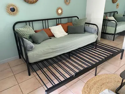 a bench with pillows on it in a room at Aix-en-Provence, Charmant studio proche toutes comodités et axes routiers, linges fournis in Aix-en-Provence