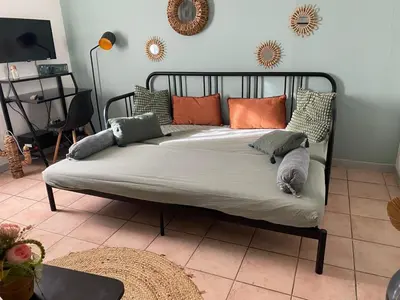 a bed with pillows on it in a room at Aix-en-Provence, Charmant studio proche toutes comodités et axes routiers, linges fournis in Aix-en-Provence