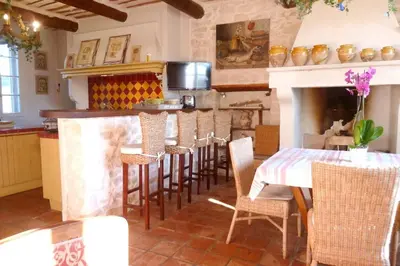 a kitchen with a table and chairs and a fireplace at Maison de 6 chambres avec piscine privée, jardin aménagé et wifi à Pernes-les-Fontaines in Pernes-les-Fontaines
