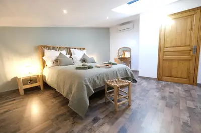 a bedroom with a large bed and a wooden floor at magnificent individual villa with heated swimming pool, in aureille, in the alpilles - 10 persons in Aureille