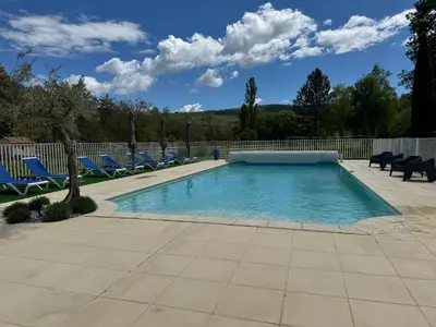 a swimming pool with blue lounge chairs in a yard at Gîte Le Tramontane Meublé de tourisme 4 étoiles Le Moulin de Prédelles in Reillanne