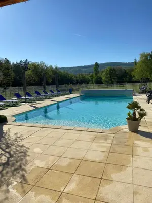 a large swimming pool with blue chairs and a fence at Gîte Le Sirocco Meublé de tourisme 4 étoiles Le Moulin de Prédelles in Reillanne