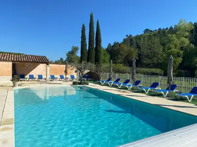 a large swimming pool with blue chairs and trees at Gîte Le Sirocco Meublé de tourisme 4 étoiles Le Moulin de Prédelles in Reillanne