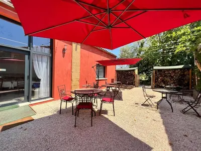 a group of tables and chairs under a red umbrella at BASTIDE DES MARTELIERES in Salon-de-Provence