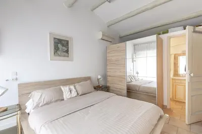 a white bedroom with a bed and a window at Les Lauriers en Lubéron in Cheval-Blanc
