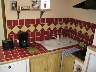 a kitchen with a sink and red tiles on the counter at Le Maset des Aires avec vue sur le Luberon et son jacuzzi extérieur disponible de juin à mi-septembre in Maubec