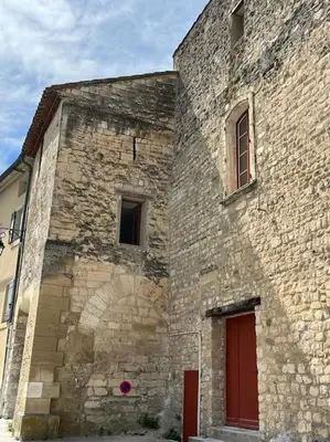 an old stone building with a red door and windows at La Planette in Venasque