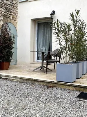 a black chair sitting on a porch with plants at Gîte Le Nathalie Meublé de tourisme 4 étoiles Le Moulin de Prédelles in Reillanne