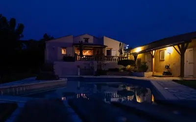 a house with a swimming pool at night at La Halte Gourmande in Vachères