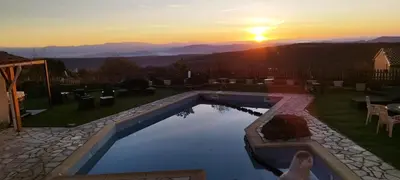 a woman standing next to a swimming pool with a sunset at La Halte Gourmande in Vachères
