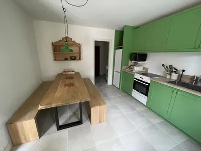 a kitchen with green cabinets and a wooden table at LES ROCHES in Apt