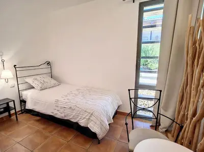 a bedroom with a bed and a window and a chair at Escale détente - Résidence 4* au sein d'un Golf in Saumane-de-Vaucluse