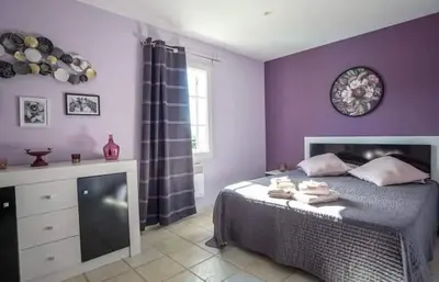 a bedroom with purple walls and a bed with towels on it at La marinette in Fontaine-de-Vaucluse