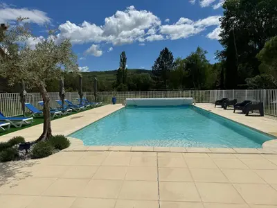 a swimming pool with blue chairs and a fence at Chambre d'hôtes Zephyr Libeccio Le Moulin de Prédelles in Reillanne