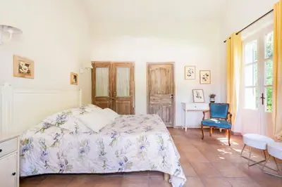 a bedroom with a bed and a blue chair at Mas de Lure in Salon-de-Provence