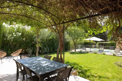 a table and chairs under an arbor in a yard at Maison Cocoon Lourmarin 6 personnes in Lourmarin