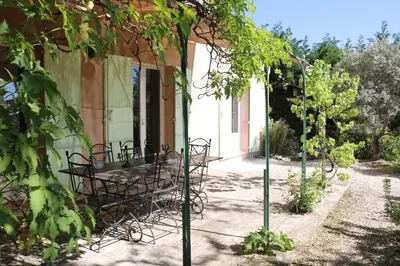 a patio with a table and chairs under a pergola at Les Chambres de Fanny in Cabrières-dʼAigues