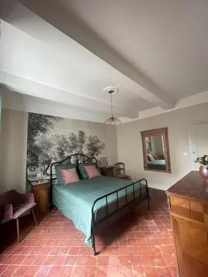 a bedroom with a bed with a painting on the wall at Maison Rosiris in Pernes-les-Fontaines