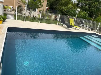 a swimming pool with blue water and some chairs at Villa climatisé avec piscine et jacuzzi in Carpentras