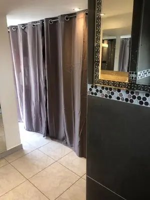a bathroom with gray shower curtains and a mirror at Villa climatisé avec piscine et jacuzzi in Carpentras