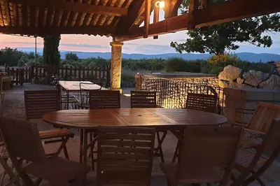 a wooden table and chairs under a pergola at Maison de caractère dans Luberon avec piscine in Saignon